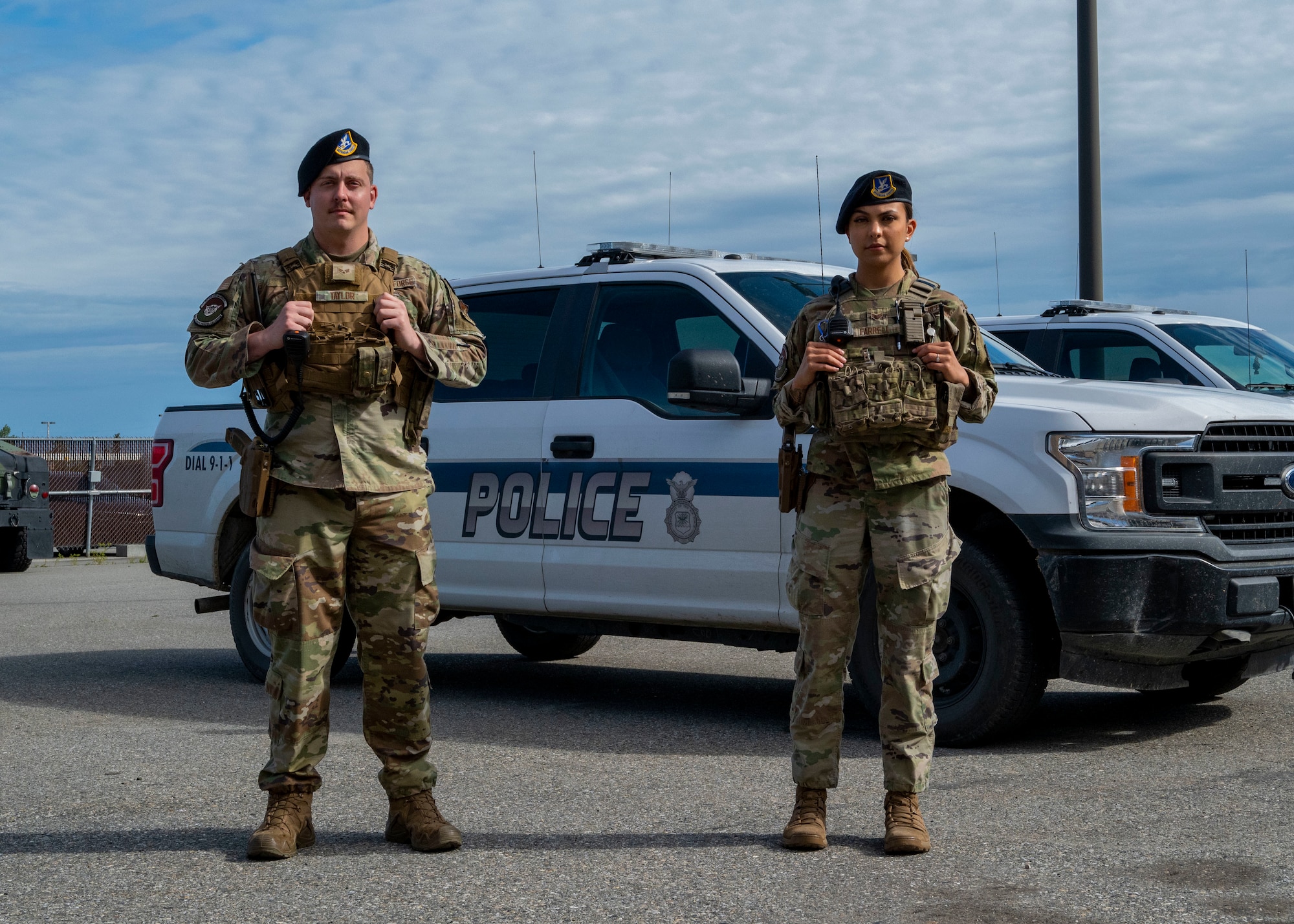Senior Airmen Alan Taylor, a 354th Security Forces Squadron (SFS) response force leader, and Precious Farrell, a 354th SFS alarm monitor, stand in front of a police vehicle July 11, 2023, on Eielson Air Force Base, Alaska. Taylor and Farrell were vital to the rescue of a family threatened by an aggressive moose and her calf. (U.S. Air Force photo by Staff Sgt. Beaux Hebert)