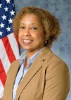 Photo of a woman with a warm and engaging smile in front of an American flag