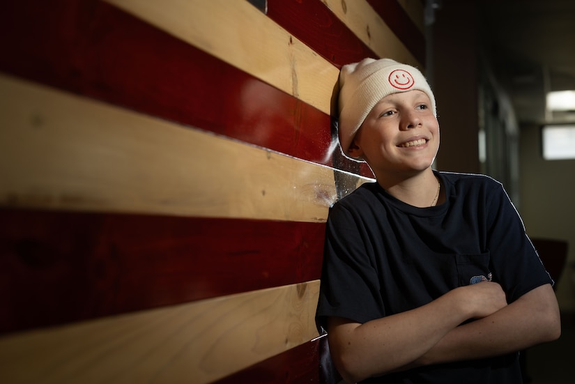 A young boy wearing a T-shirt and a beanie poses for a portrait.