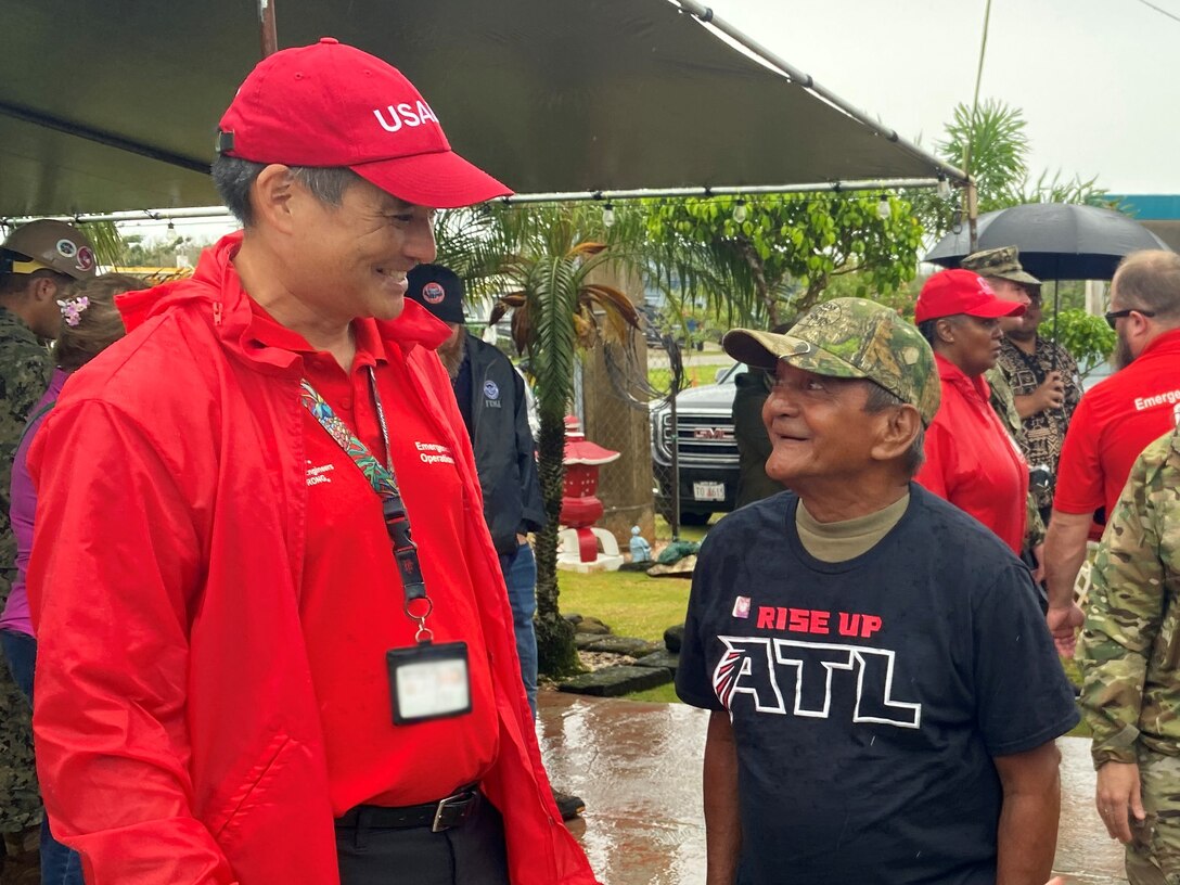 RISEUP Roofing Mission Manager Alan Kato talks to RISEUP roof recipient Gerald Baza following the completion of the final metal roof installation by Task Force RISEUP in response to Typhoon Mawar at the recipient’s home in Dededo, Guam July 27. The U.S. Department of Defense and the U.S. Army Corps of Engineers, in coordination with the Federal Emergency Management Agency and the U.S. Territory of Guam, launched the Roofing Installation Support Emergency Utilization Program, or RISEUP, to help temporarily repair metal roofs damaged by Typhoon Mawar, which made landfall May 24. (This photo has been modified to blur the badge)