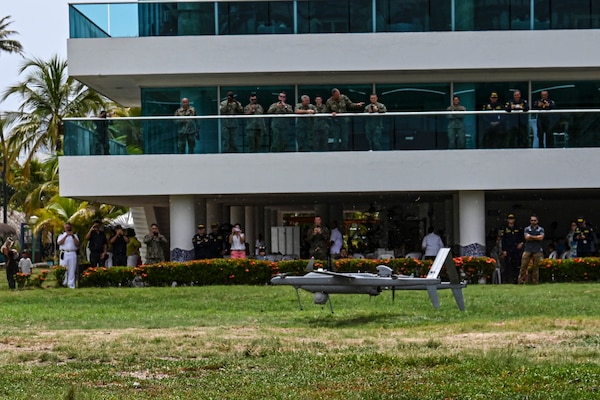 Photos of NITAS members from Colombia and the Republic of Korea discuss the Aerosonde MK4.7 Hybrid Quad unmanned aerial vehicle during demonstration of at the Club Naval Castillogrande during UNITAS LXIV, July 16, 2023.