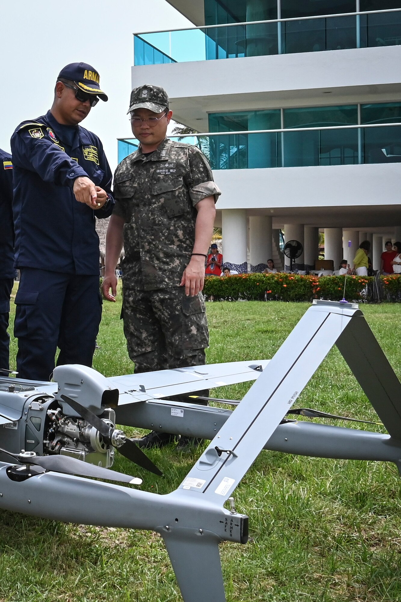 Photos of NITAS members from Colombia and the Republic of Korea discuss the Aerosonde MK4.7 Hybrid Quad unmanned aerial vehicle during demonstration of at the Club Naval Castillogrande during UNITAS LXIV, July 16, 2023.