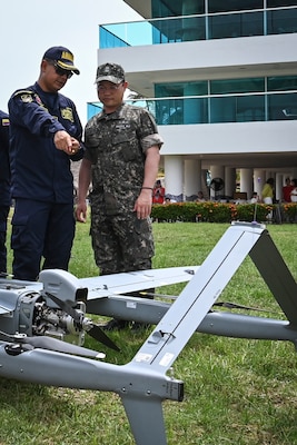 Photos of NITAS members from Colombia and the Republic of Korea discuss the Aerosonde MK4.7 Hybrid Quad unmanned aerial vehicle during demonstration of at the Club Naval Castillogrande during UNITAS LXIV, July 16, 2023.