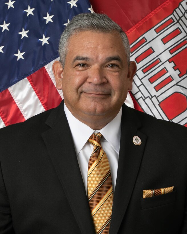 Man in blazer with tie in front of flags