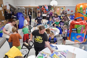 Military families browsing school supplies laid out on a room full of tables.