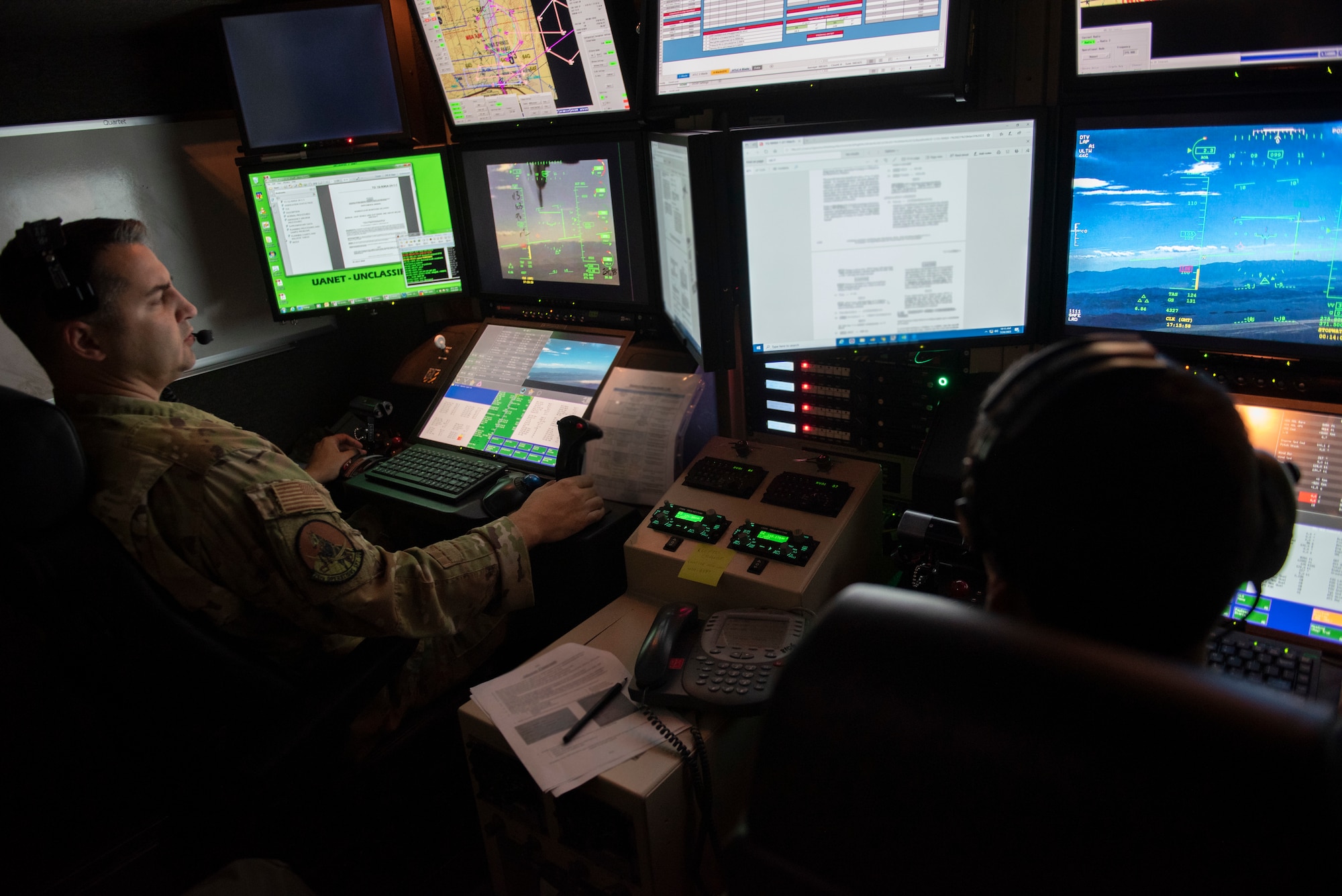 A pilot and a sensor operator pilot an MQ-9 inside in a GSC.