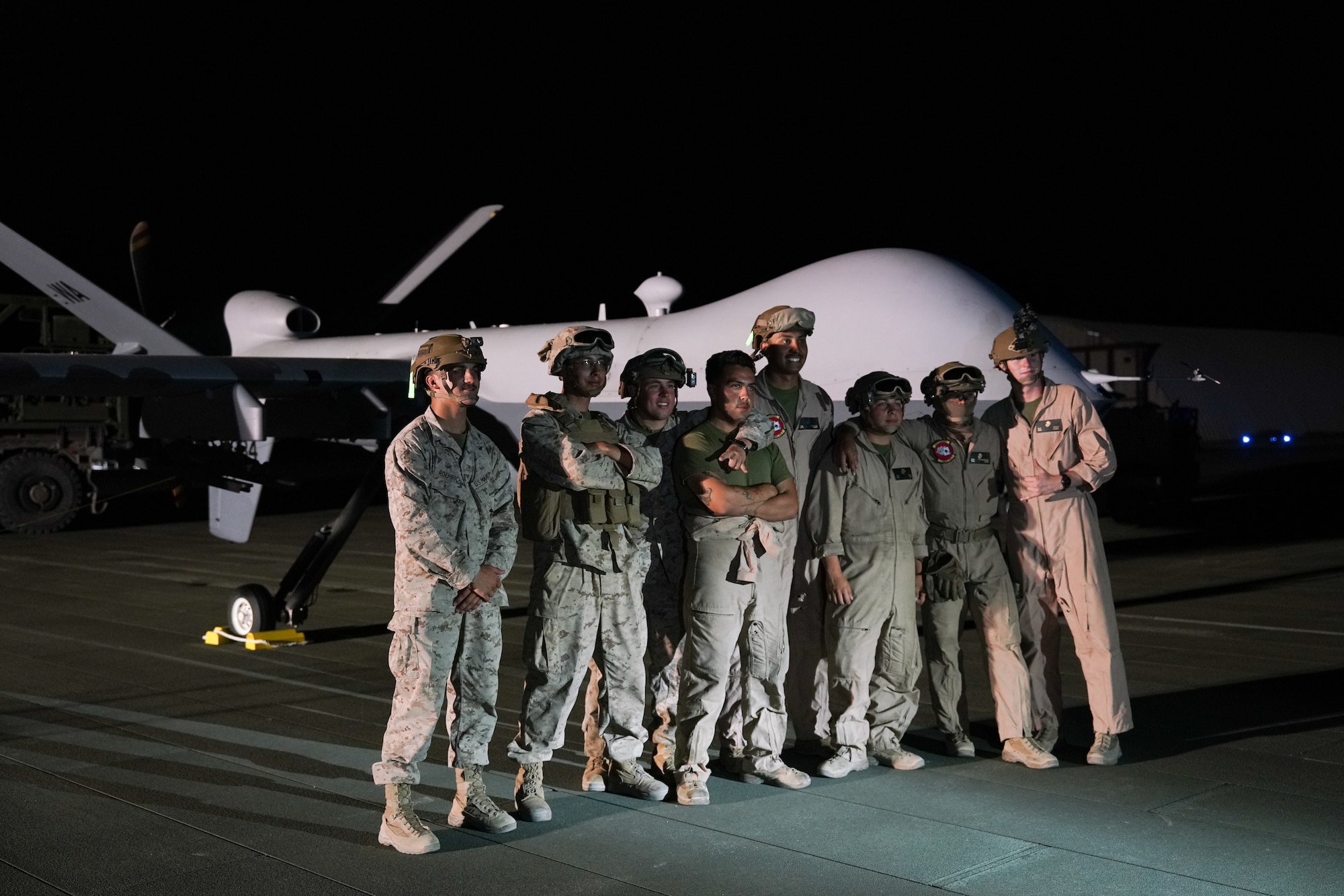 Eight Marines pose in front of an MQ-9 Reaper for a group photo.