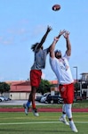 student and coach mid air trying to catch a football