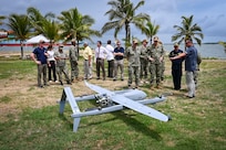 Photos of NITAS members from Colombia and the Republic of Korea discuss the Aerosonde MK4.7 Hybrid Quad unmanned aerial vehicle during demonstration of at the Club Naval Castillogrande during UNITAS LXIV, July 16, 2023.