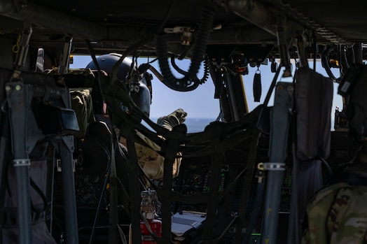  Point of view from back of a helicopter, aimed at the pilot in the cockpit, pointing through the windshield.