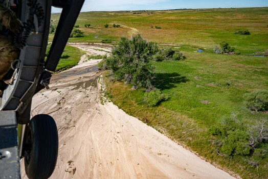  Point of view photo from the side of a helicopter flying over a ravine.