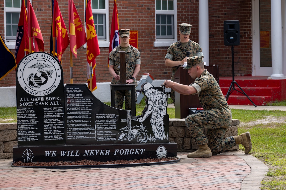 U.S. Marines and Sailors with 2d Light Armored Reconnaissance Battalion (LAR), 2d Marine Division place dog tags of fallen service members on a memorial display during a memorial service on Camp Lejeune, North Carolina, May 25, 2023. The service commemorates past service members from 2d LAR by placing the dog tags of the Marines and Sailors that gave their lives from 1989 to 2011 on a Soldiers Cross. (U.S. Marine Corps photo by Pfc. Jessi Stegall)