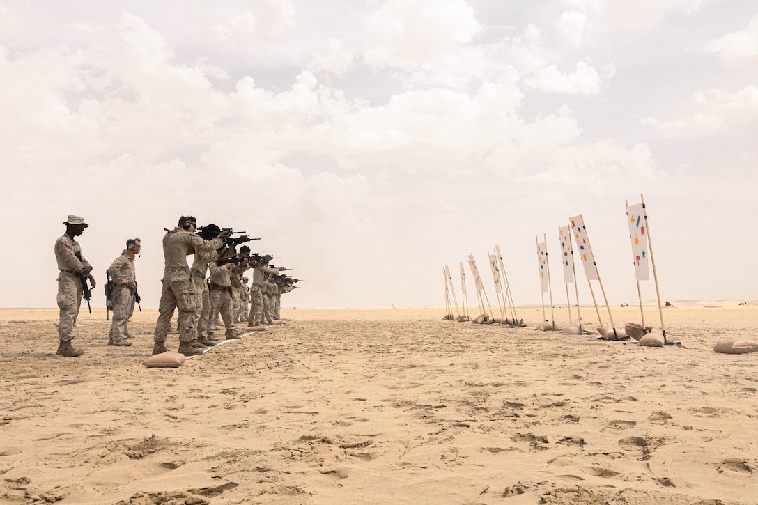 Marines shoot at targets in the desert.