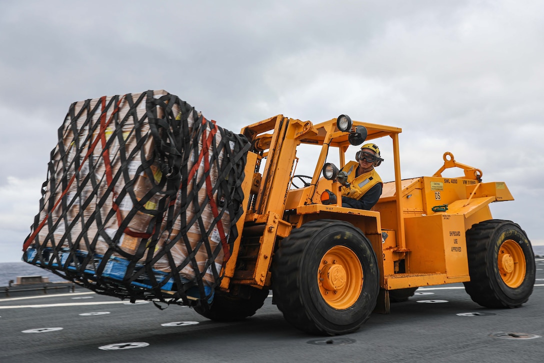 A sailor operates a forklift aboard a Navy ship.