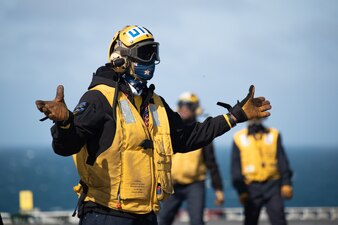 Aviation Boatswain's Mate (Handling) 1st Class Alex Williams, from Houston, assigned to the world's largest aircraft carrier USS Gerald R. Ford's (CVN 78) air department, signals to an aircraft on the flight deck, May 31, 2023.