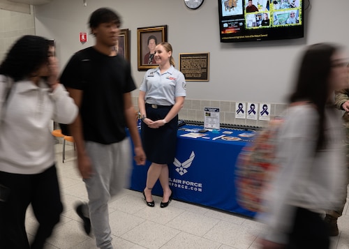 Image of Airman at a school with students walking by.