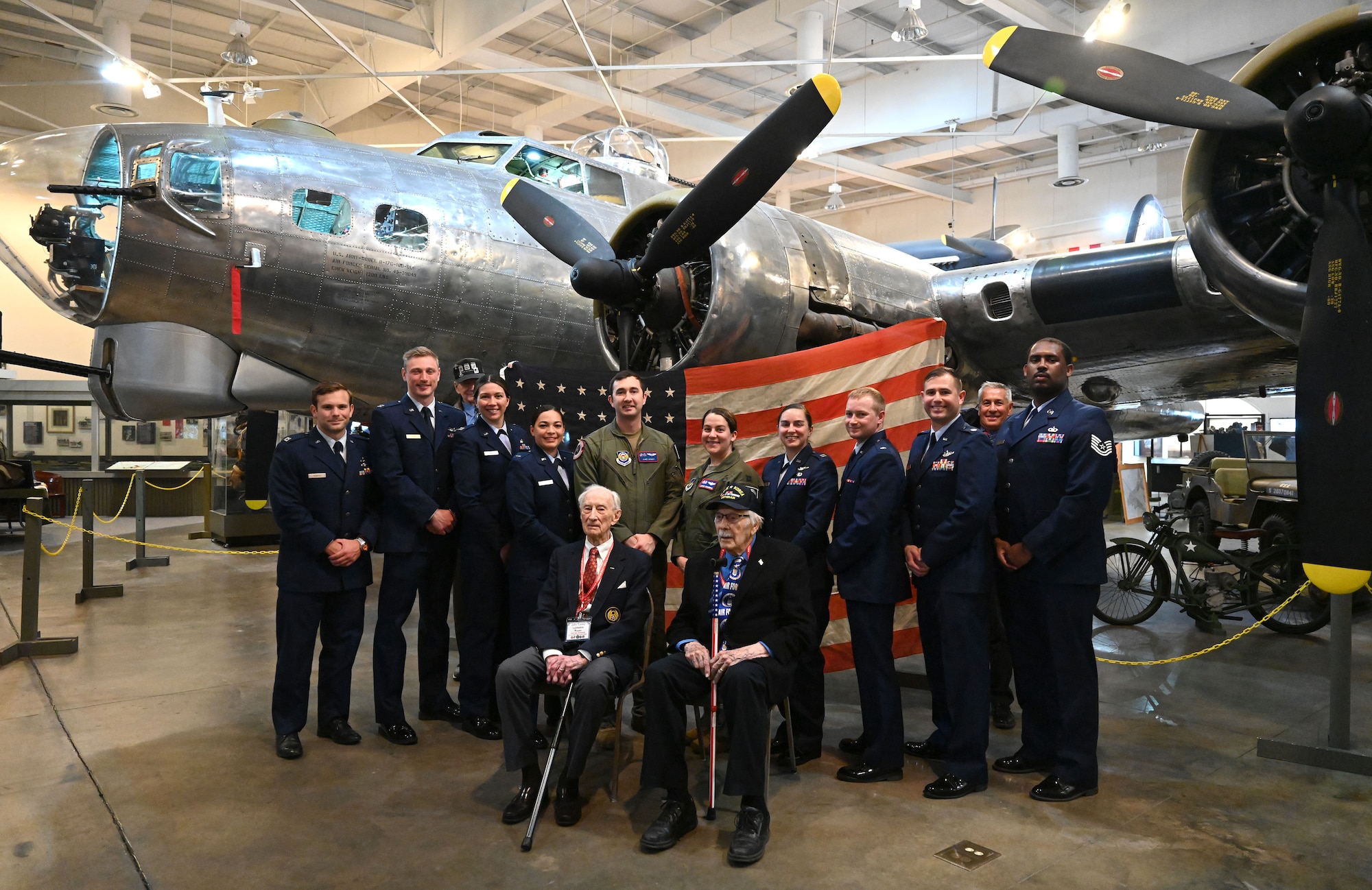 U.S. Air Force Airmen from Royal Air Force Mildenhall, along with 100th Bomb Group veterans and survivors, Capt. John “Lucky” Luckadoo, seated left, 351st Bomb Squadron pilot and operations officer, and Lt James Rasmussen, 349th Bomb Squadron navigator, and two sons of 100th BG veterans pose for a photo by a restored B-17 Flying Fortress, “The City of Savannah,” with the original flag that was flown over the 100th Bomb Group at Thorpe Abbotts during World War II, at the National Museum of the Mighty Eighth Air Force in Savannah, Georgia, May 27, 2023. When Thorpe Abbotts was decommissioned as a U.S. base in 1945, the flag was lowered. It has since been brought to every reunion since it began. (U.S. Air Force photo by Karen Abeyasekere)