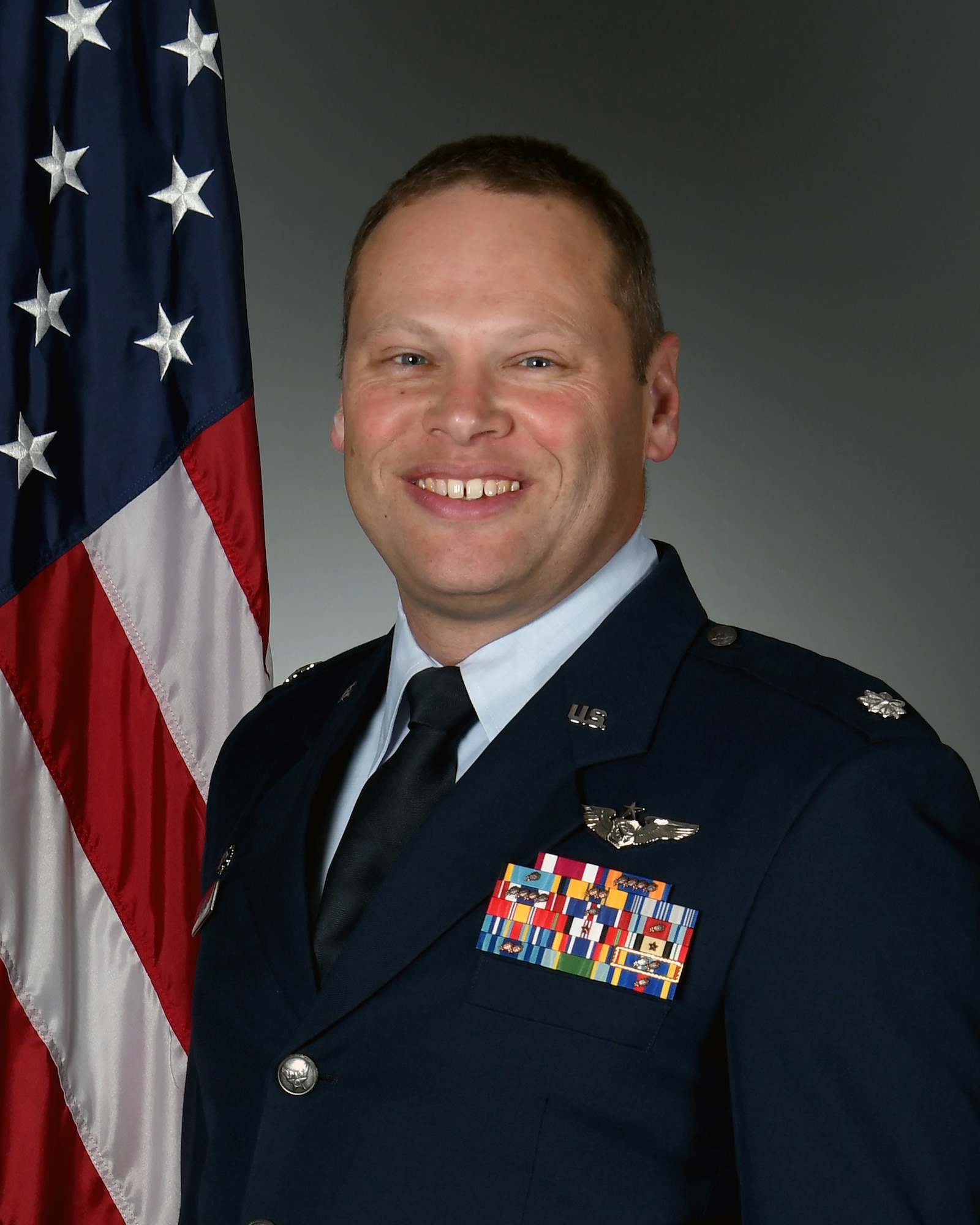 photo of uniformed U.S. Air Force Airman with U.S. flag in the background