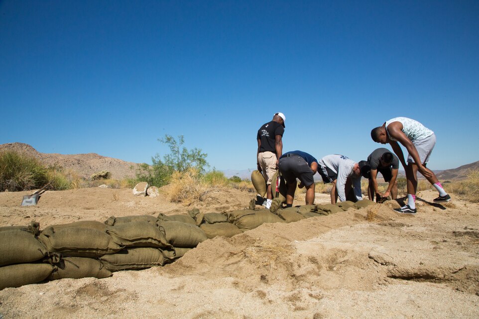 Marines and sailors place sandbags to create a retaining wall