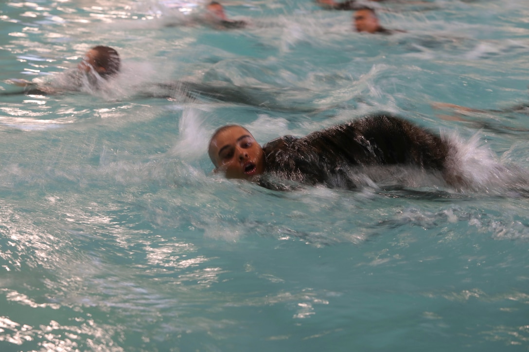 A Marine Corps recruit takes a breath while swimming in a pool with fellow recruits.