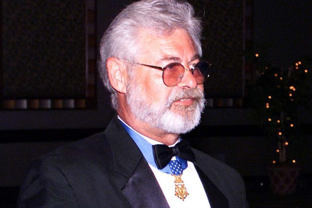 Close-up of a man wearing a tuxedo with a medal around his neck.