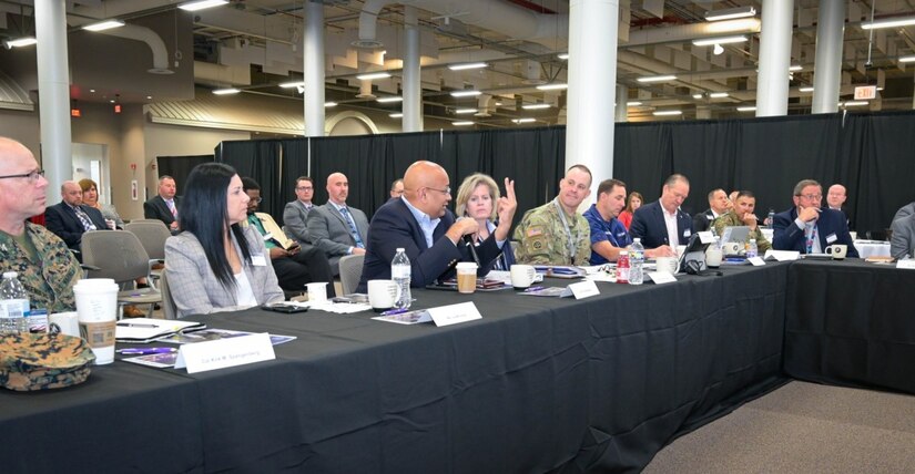 Photo of attendees sitting at a table discussing aspects of the presentations.