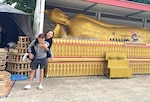 Two women pose in front of a Buddah.