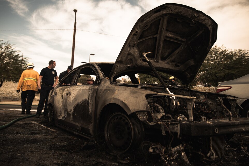 Firefighters examine a burned vehicle
