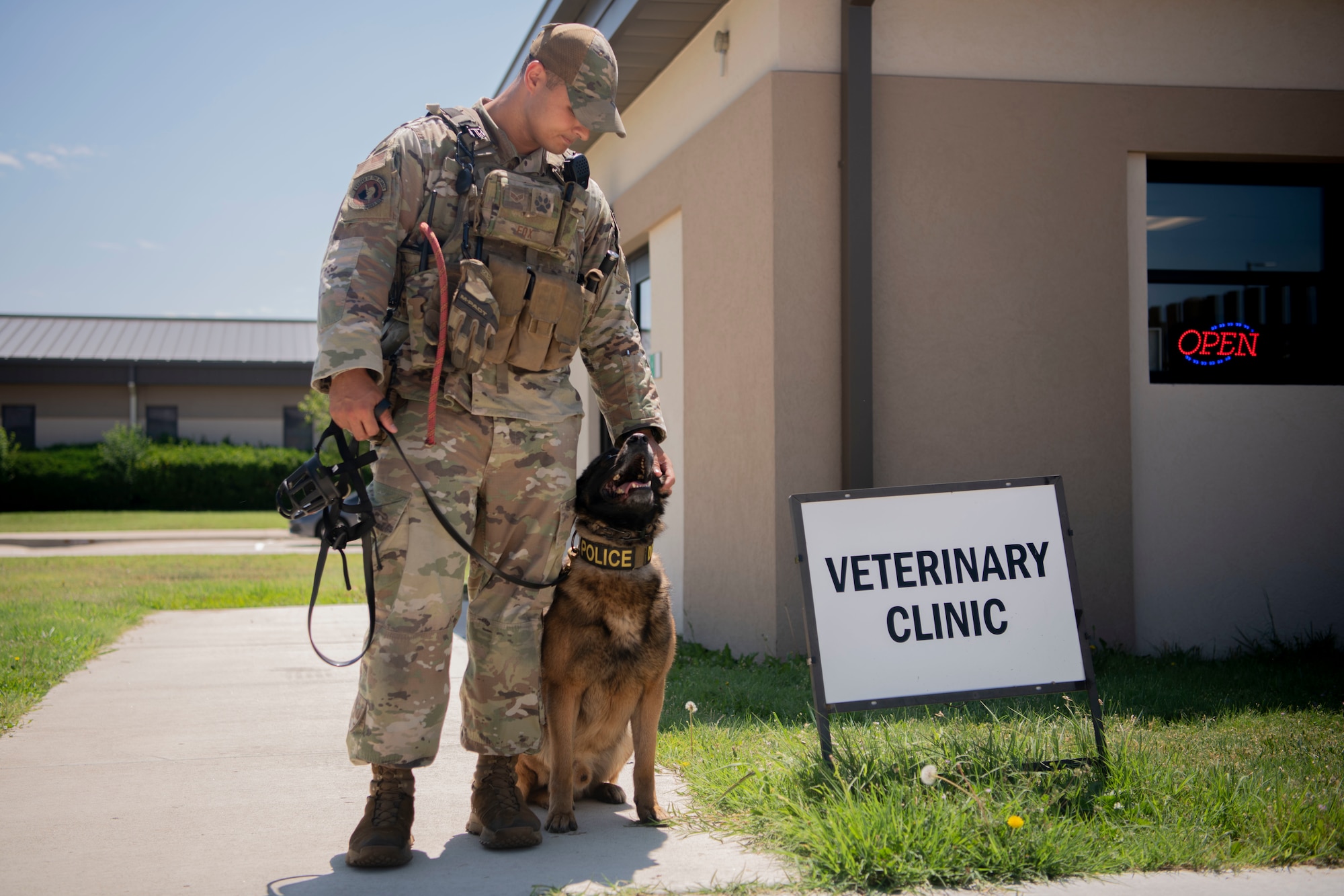 Senior Airman Joseph Fox, 22nd Security Forces Squadron military working dog handler, and military working dog Sani stand outside the veterinary clinic at McConnell Air Force Base, Kansas May 30, 2023. A team of ophthalmologists from Kansas State University's Veterinary Health Center visited McConnell, where they provided free eye exams for military working dogs.