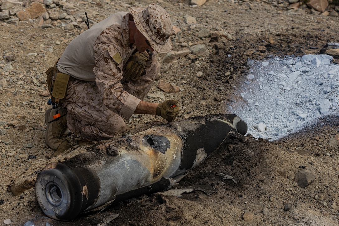 U.S. Marine with the Explosive Ordnance Disposal (EOD) Advanced Training Center scrapes off debris caused by thermite from a controlled explosive during a controlled explosive exercise at Marine Corps Air-Ground Combat Center, Twentynine Palms, California, May 10, 2023. This exercise was conducted to document how to properly set up controlled explosives and to review the aftermath of the explosives for future classes. (U.S. Marine Corps photo by Lance Cpl. Richard PerezGarcia)
