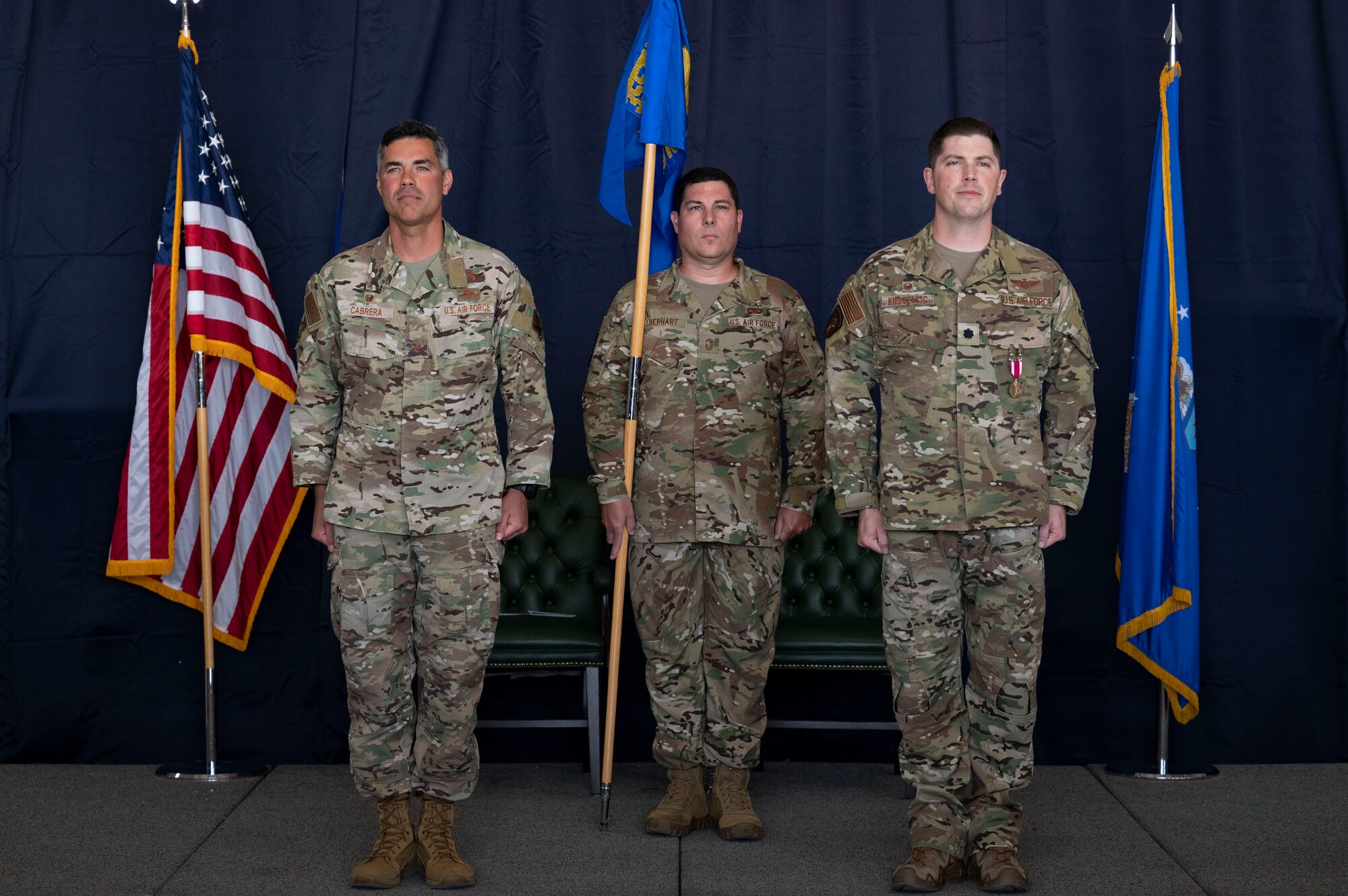 Pictured above are three men in military uniform standing on a stage.