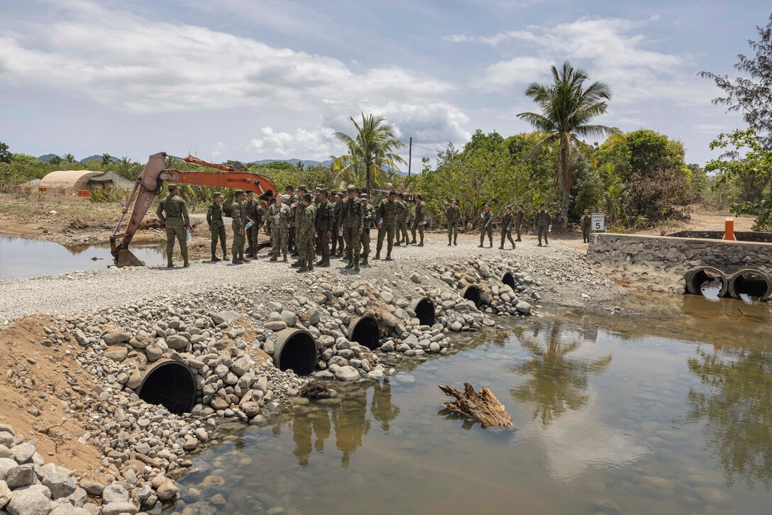 U.S. Navy Ensign Brianna Curley, a public affairs officer with Expeditionary Strike Group 3, demonstrates a recently contructed bridge to cadets of the Philippine Army during a tour of Camp Agnew, Casigueran, Philippines in preparation for Balikatan 23 on April 3, 2023. Balikatan is an annual exercise between the Armed Forces of the Philippines and U.S. military designed to strengthen bilateral interoperability, capabilities, trust, and cooperation built over decades shared experiences. (U.S. Marine Corps photo by SSgt. Danny Gonzalez)