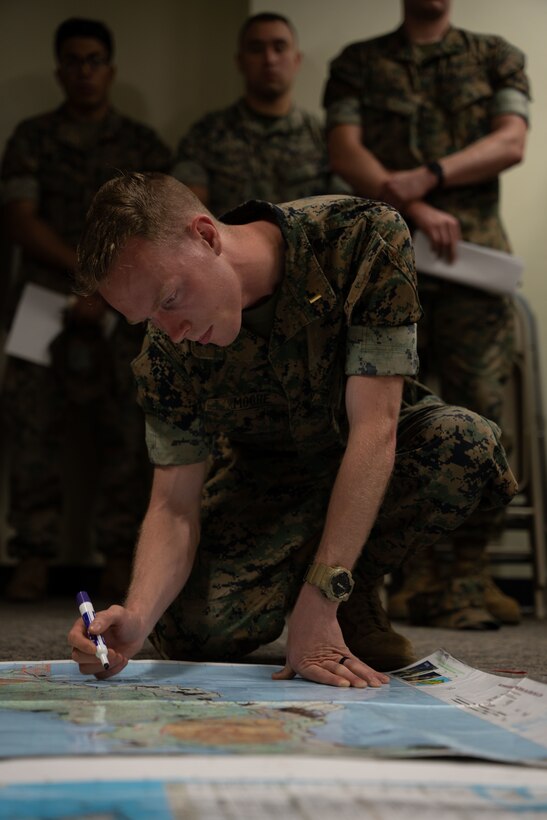 U.S. Marine Corps 2nd Lt. Robert Moore, a platoon commander with Combat Logistics Battalion 4, draws tactical routes on a map for a rehearsal of concepts brief in preparation for an upcoming Marine Corps Combat Readiness Evaluation at Camp Schwab, Apr. 21, 2023. A ROC “walk” is the last step in the planning process for an exercise or operation where commanders and relevant military personnel go over every detail of the exercise or operation to ensure every participant knows their role to achieve mission success. (U.S. Marine Corps photo by Cpl. Madison Santamaria)