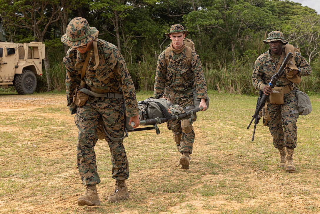 U.S. Marines and Sailors across 3rd Marine Logistics Group escort a simulated casualty to safety for a mass casualty drill during a Marine Corps Combat Readiness Evaluation at Camp Hansen, Okinawa, Japan, April 26, 2023. 3rd Marine Logistics Group, based out of Okinawa, Japan, is a forward-deployed combat unit that serves as III MEF’s comprehensive logistics and combat service support backbone for operations throughout the Indo-Pacific area of responsibility. (Marine Corps photo by Lance Cpl. Weston Brown)