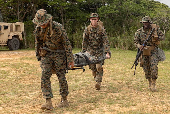 U.S. Marines and Sailors across 3rd Marine Logistics Group escort a simulated casualty to safety for a mass casualty drill during a Marine Corps Combat Readiness Evaluation at Camp Hansen, Okinawa, Japan, April 26, 2023. 3rd Marine Logistics Group, based out of Okinawa, Japan, is a forward-deployed combat unit that serves as III MEF’s comprehensive logistics and combat service support backbone for operations throughout the Indo-Pacific area of responsibility. (Marine Corps photo by Lance Cpl. Weston Brown)