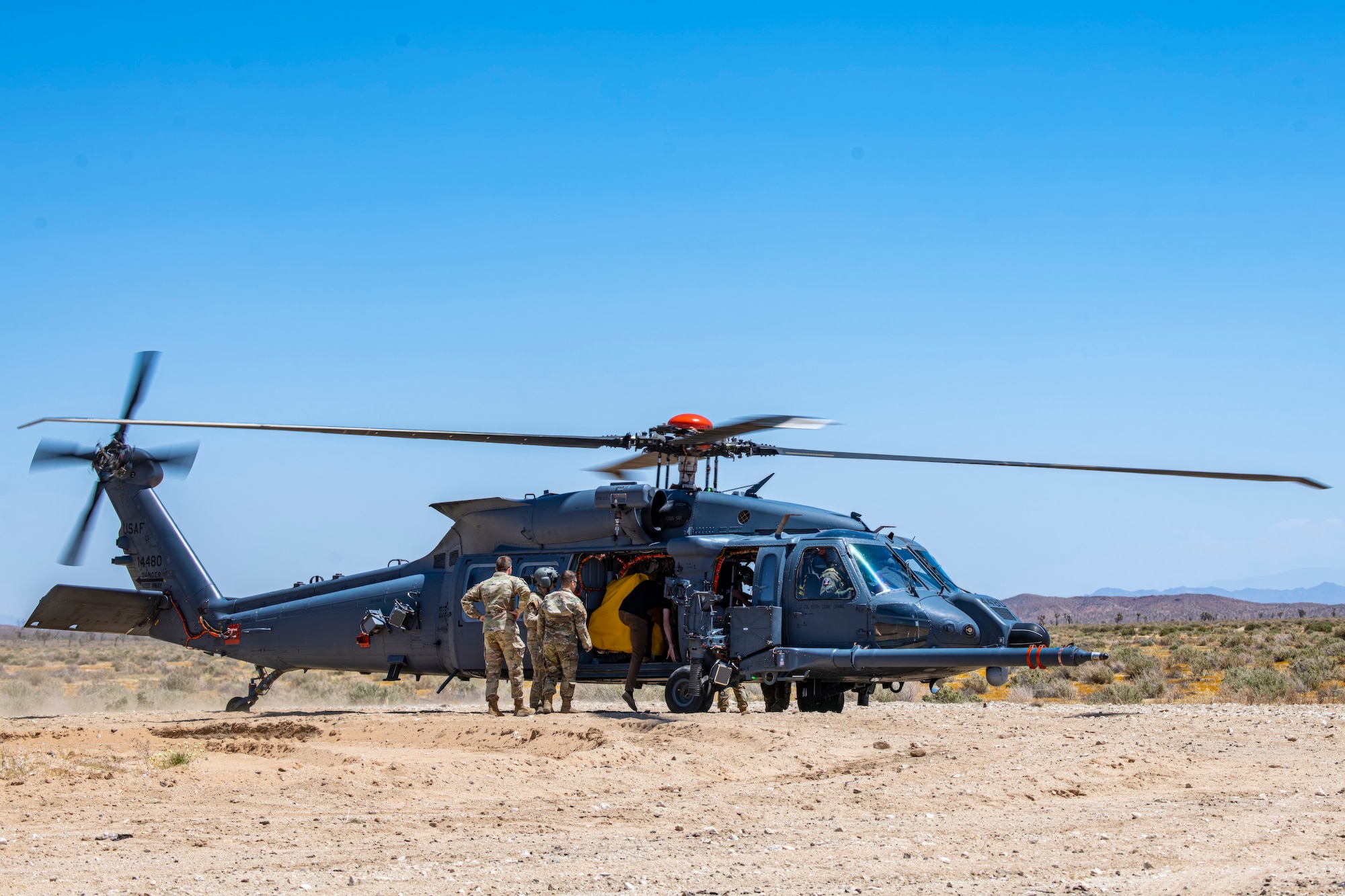 U.S. Air Force Test Pilot School Space Test Course Class 23-1 students board an HH-60W Jolly Green II helicopter at the Precision Impact Range Area on Edwards Air Force Base, California, May 10. As part of the USAFTPS STC Class 23-1 capstone project, the students utilized the helicopters to conduct simulated combat search and rescue operations using multi-domain imagery assets. (Air Force photo by Giancarlo Casem)