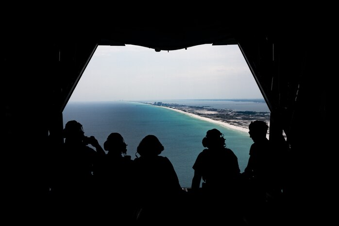 People sitting on the ramp of an MC-130 Aircraft, overlooking the gulf coast