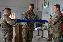 Pictured above is three men rolling up a flag.