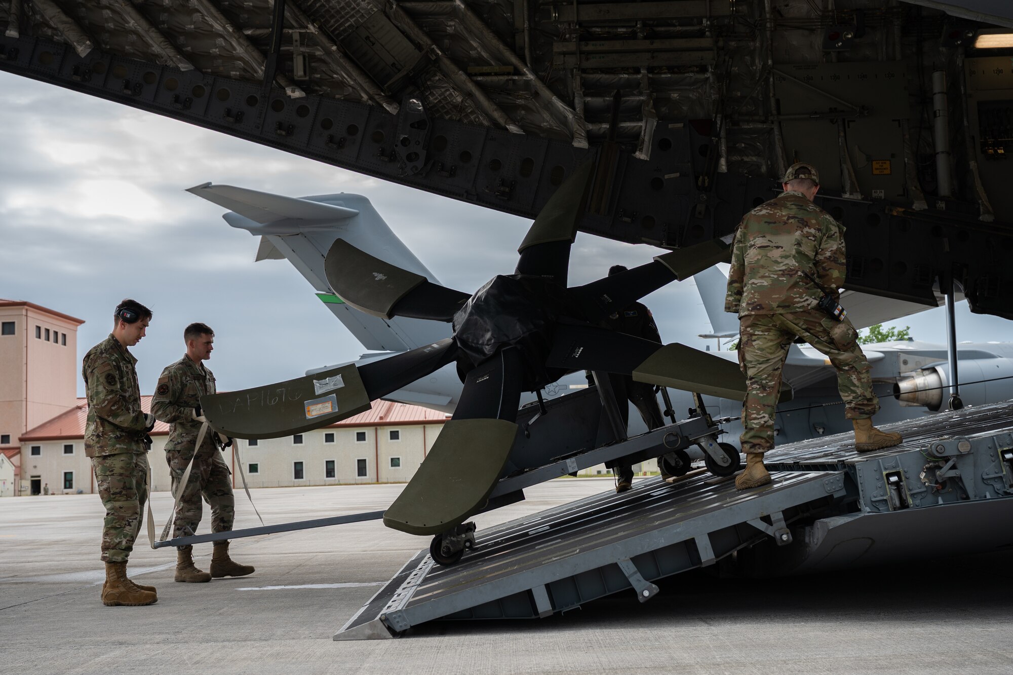 Airmen from the 724th Air Mobility Squadron, 190th Air Refueling Wing, 62nd Aircraft Maintenance Squadron, and 7th Air Mobility Squadron, load an aircraft propeller onto a C-17 Globemaster III at Aviano Air Base, Italy, May 16, 2023, in support of Defender Exercise 23.
