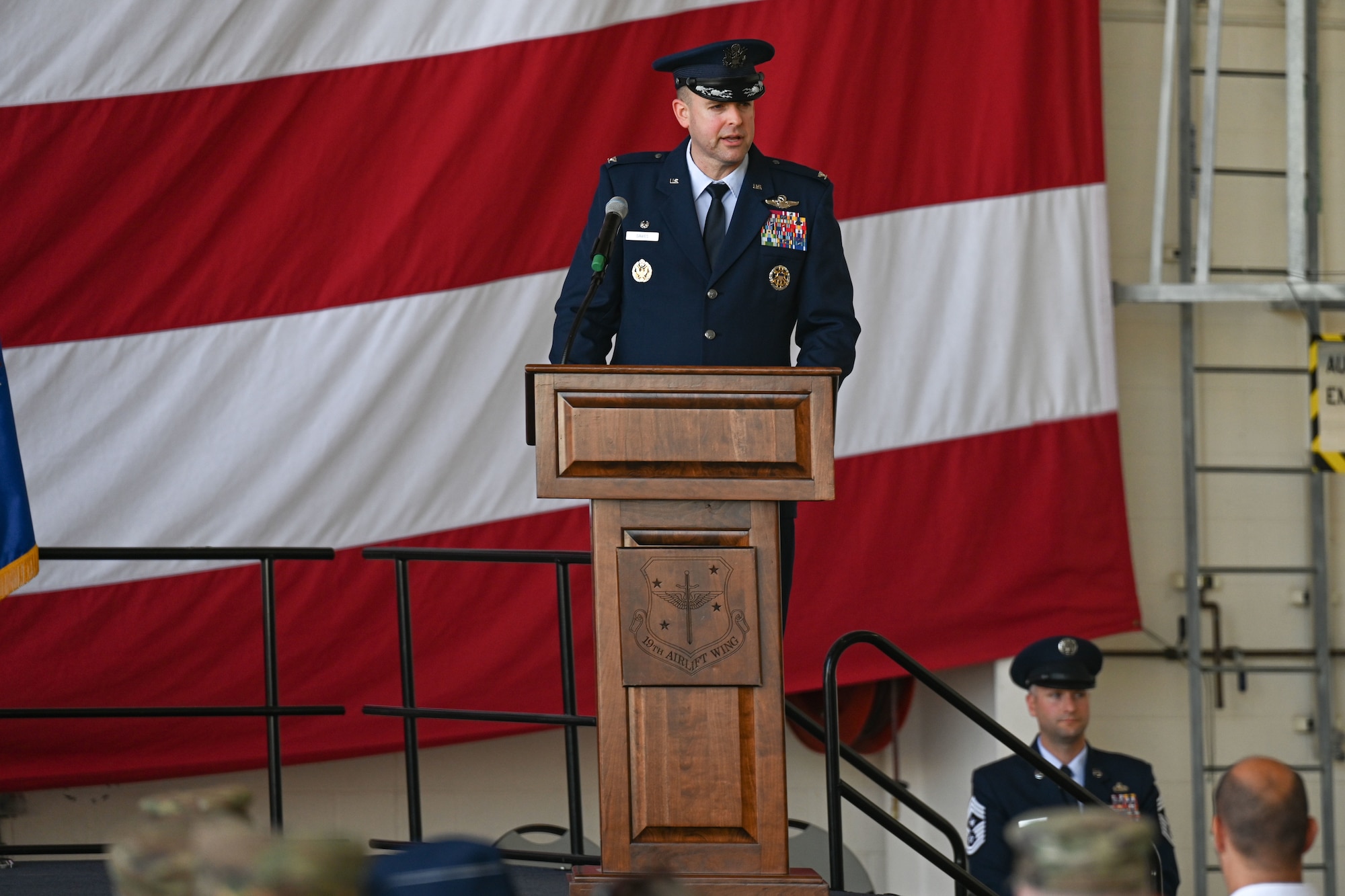 Airmen from the 19th Airlift Wing participate in a change of command ceremony in an airplane hangar