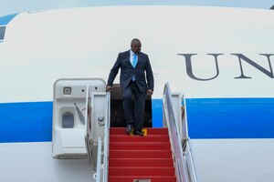 A man in a suit exits a large passenger plane stairs