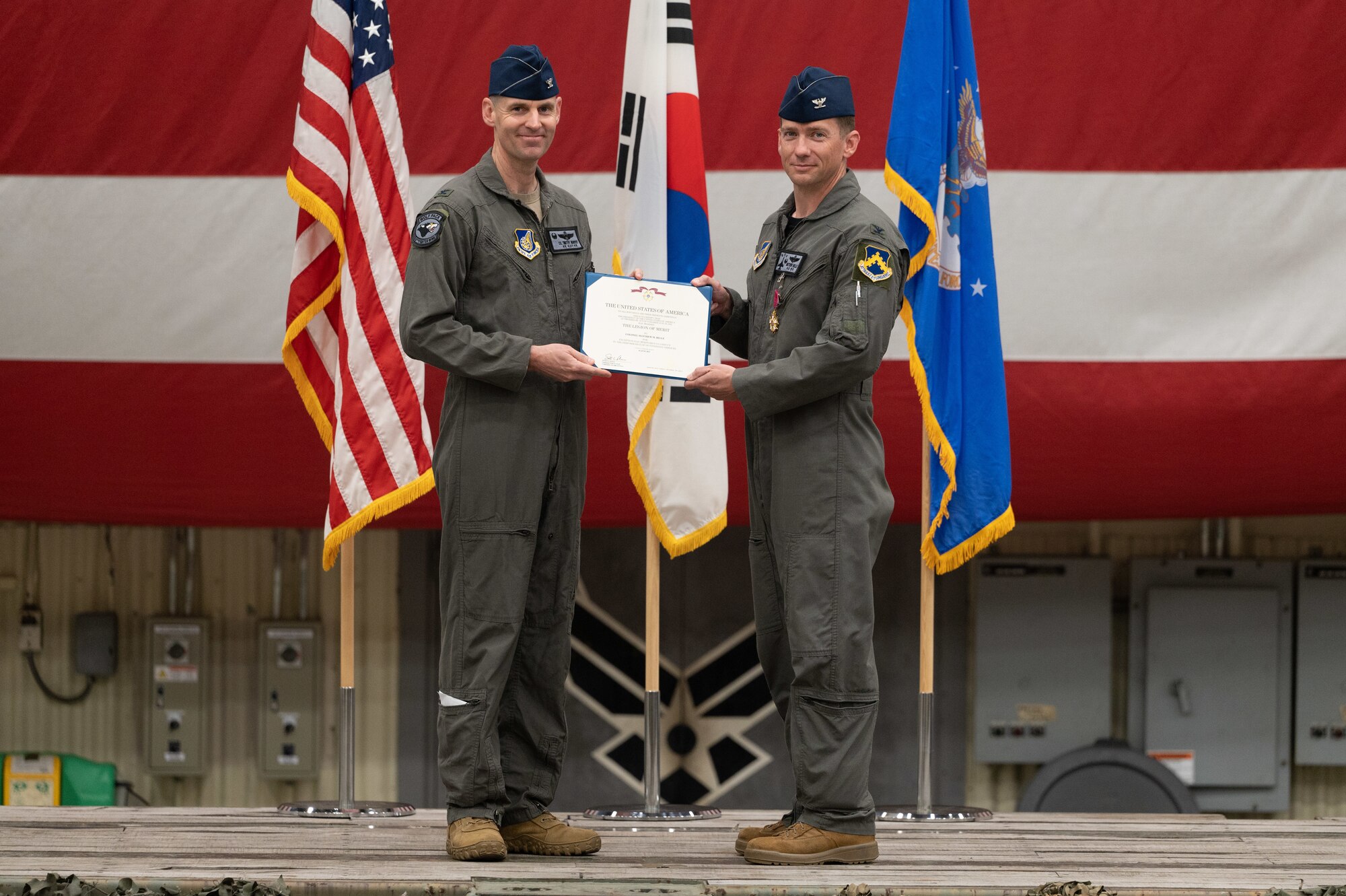 Col. Timothy B. Murphy, left, 8th Fighter Wing commander, holds a decoration awarded to Col. Matthew Belle, 8th Operations Group outgoing commander, during a change of command ceremony at Kunsan Air Base, Republic of Korea, June 2, 2023. The 8th OG commander is responsible for conventional air-to-ground and air-to-air missions in support of armistice and wartime taskings to defend the Republic of Korea. (U.S. Air Force photo by Staff Sgt. Sadie Colbert)