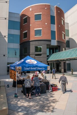 People visit a stand at a farmers market.