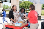 People visit a stand at a farmers market.