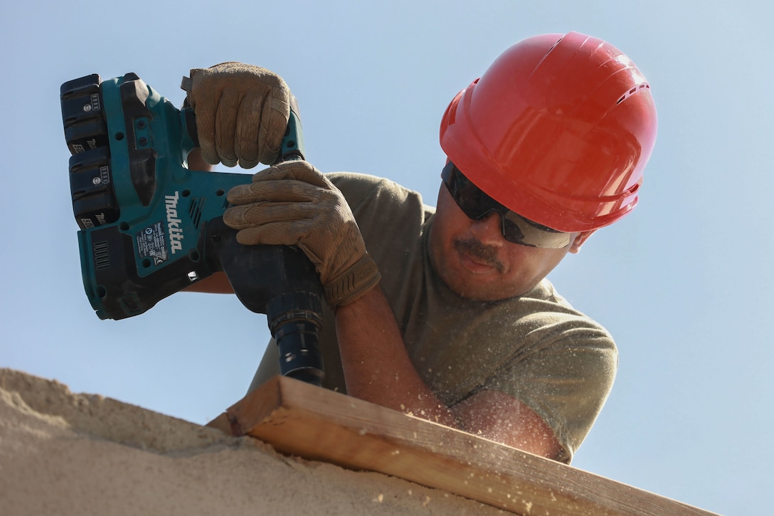 A soldier wearing a hard hat works on a roof.