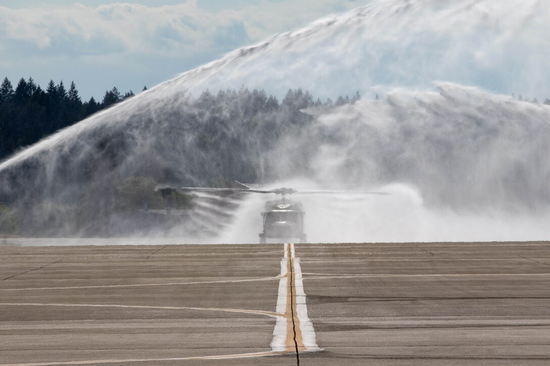 Water is sprayed onto a helicopter on a runway.