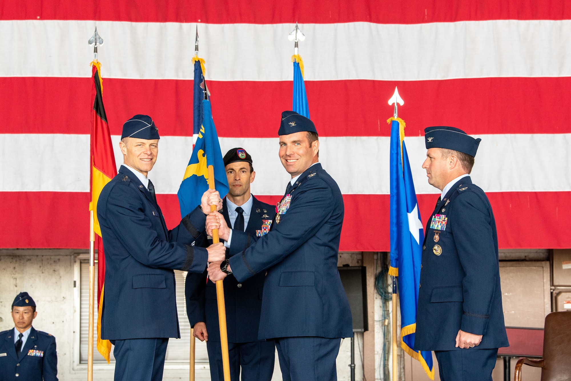 U.S. Air Force Col. Leslie Hauck, 52nd Fighter Wing outgoing commander (right), passes the 52nd FW guidon to U.S. Air Force Maj. Gen. Derek France, commander of Third Air Force, during the 52nd FW change of command ceremony