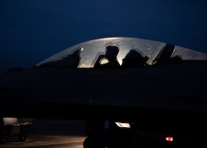 An Airman performs checks in the cockpit of an F-16C Fighting Falcon on a makeshift flightline during a training exercise.