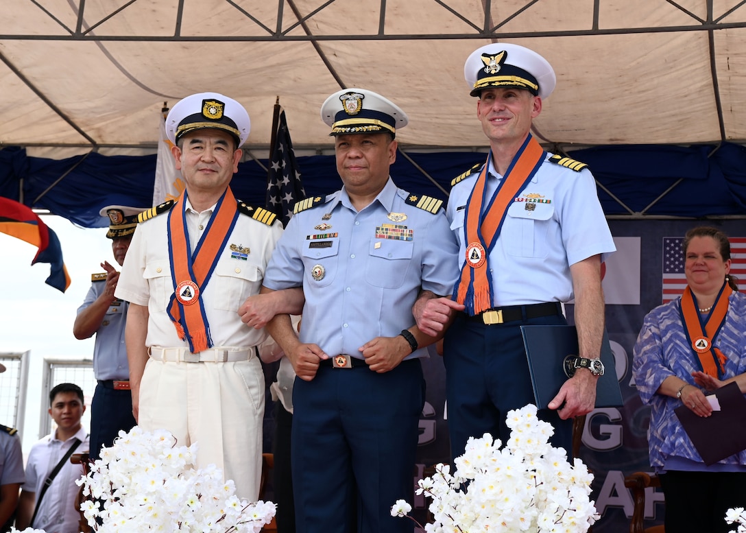 (From right) Capt. Brian Krautler, commanding officer of U.S. Coast Guard Cutter Stratton (WMSL 752), Capt. Antonio Sontillanosa, commanding officer of Philippine Coast Guard vessel BRP Melchora Aquino (MRRV-9702) and Capt. Toru Imai, commanding officer of Japan Coast Guard Vessel Akitsushima (PLH 32), stand together arm-in-arm at a ceremony in Manila, Philippines, marking the beginning of a multi-day trilateral engagement June 1, 2023. Stratton deployed to the Western Pacific to conduct engagements with regional allies and partner nations, reinforcing a rules-based order in the maritime domain.  (U.S. Coast Guard photo by Chief Petty Officer Matt Masaschi)
