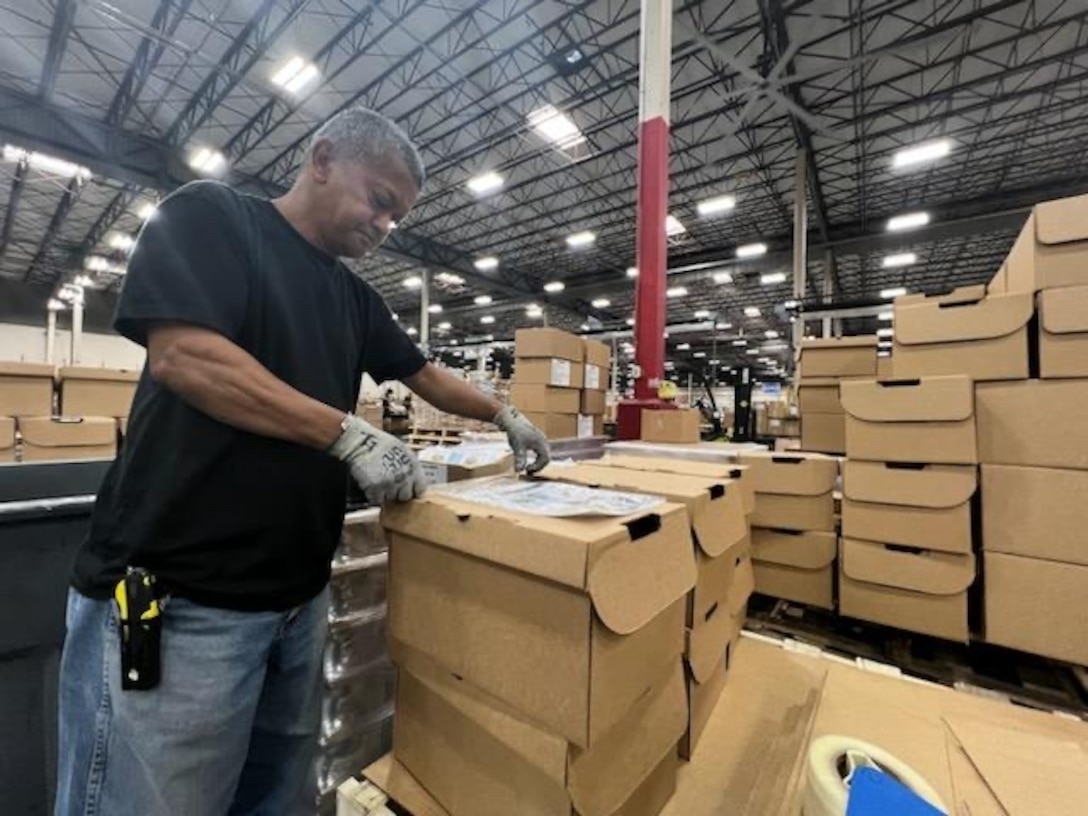 Thomas Giron tapes instructions on top of an Express Ration box on May 22, 2023.